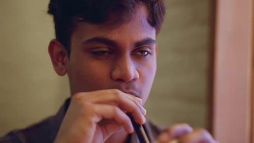 Young Man Sipping Iced Coffee Drink Indoors
