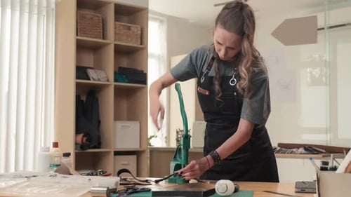 Artisan utilisant une presse à main pour fixer des rivets sur une ceinture en cuir