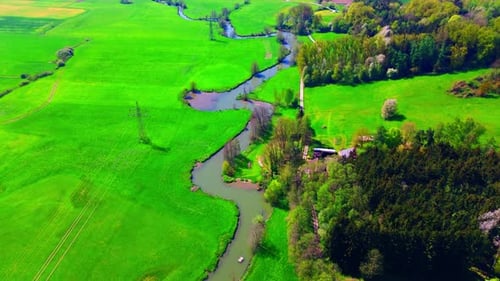 Aerial View of Serpentine River Flowing Through Green Fields and Forest