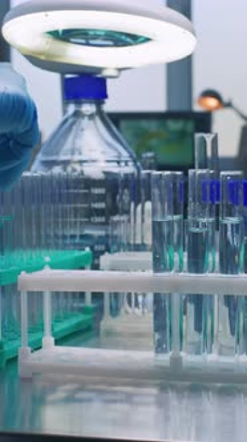 Close Up of Scientist Putting Test Tubes with Blue Liquid in Rack