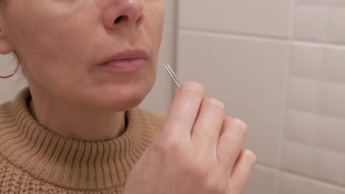 Woman Plucking Facial Hair with Tweezers Close Up