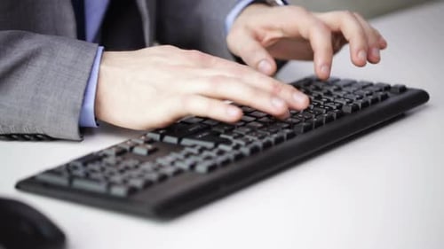 Businessman hands typing on computer keyboard in modern office workplace