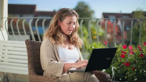 Telearbeit: Junge Frau sitzt auf einem bequemen Stuhl und tippt auf einer Computertastatur