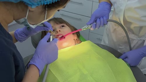 A Doctor Dentist in a Medical Mask and Blue Rubber Gloves Puts a Seal on a Little Boy Toddler Dental