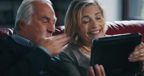 Close up of happy mature senior couple Having video call with a tablet in living room at home. Eld