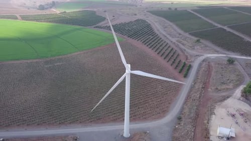 Aerial footage of Wind turbines spinning, in a mountain forest surrounding
