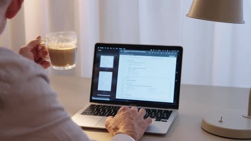 Working on laptop while drinking coffee at desk