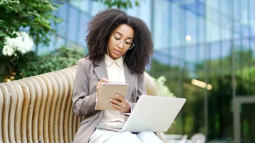 Woman Working on Laptop, Taking Notes Outdoors