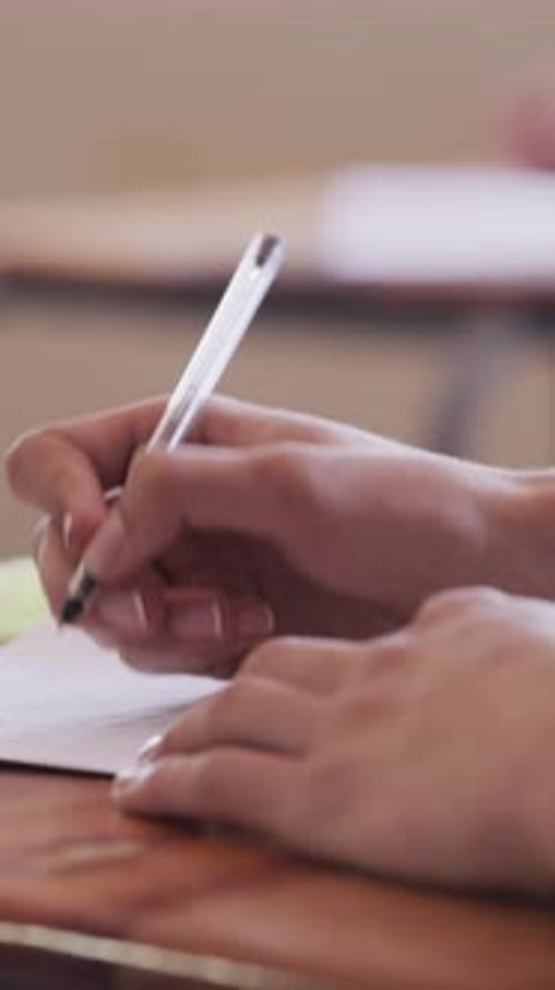 Student Hand Writes on Paper at School Desk