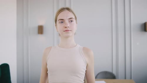 Young Woman Stretching Arm in Brightly Lit Room