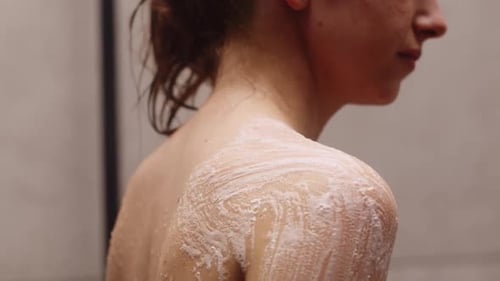 Woman Cleans Body with Soap and Sponge in Shower