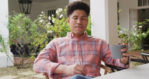Video of biracial man drinking coffee in the garden