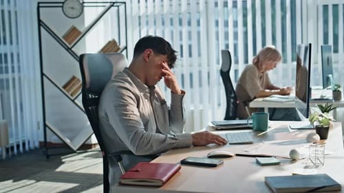 Frustrated Young Adult Working at Desk in Modern Office