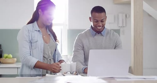 Couple Using Laptop and Drinking Coffee in Kitchen