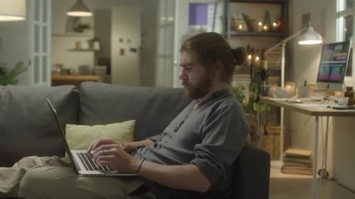 Man on Couch Types on Laptop