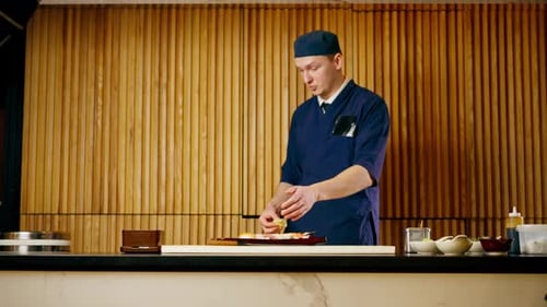in Japanese Restaurant the Chef Lays Out Pieces of Raw Fish on a Long Red Plate
