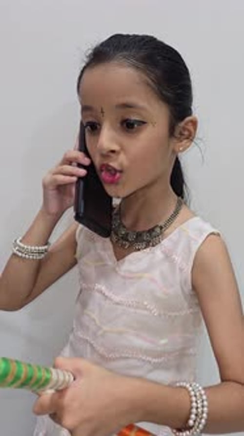 Joyeuse fille indienne en sari traditionnel du Rajasthan utilisant un smartphone contre un mur blanc