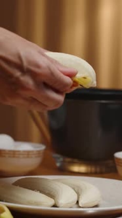 Vertical video. A woman is preparing dessert, she is peeling bananas, bowls with ingredients