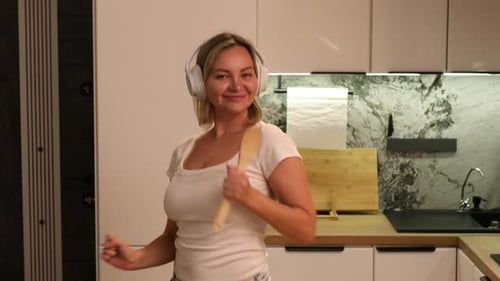 Woman with Headphones Dancing and Singing in Kitchen