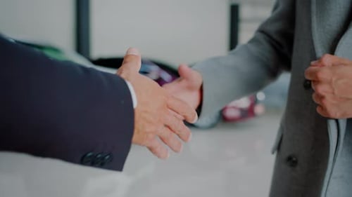 Customer and Salesman Shake Hands Making Deal in Car Dealership