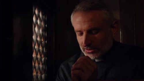 Man Praying in Dark Confessional Booth Close-Up