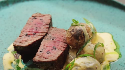 Juicy Medium Beef Meat Rib Eye Steak Slices with Baked Potato in Expensive Modern Fusion Restaurant