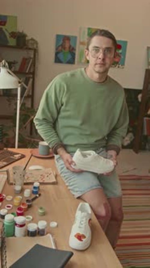 Young Adult Customizing Tennis Shoes in Home Studio