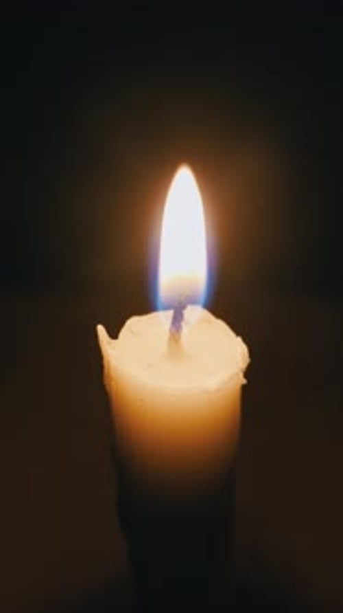 Lit Candle Flame Burning Brightly in Dark Room