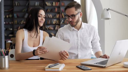 Woman and Man Collaborating on Laptop at Desk