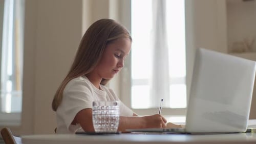 Girl Writes at Table with Laptop and Water