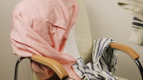 Clothing Piled onto Armchair in Indoor Setting
