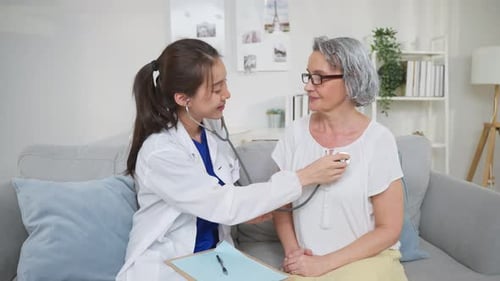 Doctor Listens to Senior Patient with Stethoscope Indoors