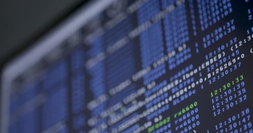 Close-up view of computer screen displaying stock market data in blue and green text