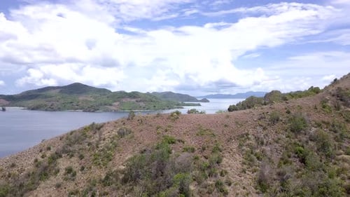 Beautiful Aerial view orbiting an island with a guy standing on top of the hill surrounded islands o