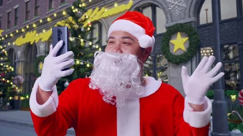 Close Up Of Asian Santa Claus Having A Video Conference Call Over Smart Phone In Christmas Night