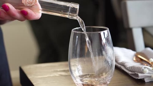 Rose Wine Poured into Stemless Wine Glass and Picked Up from Table to be Served, Close up of Woman’s