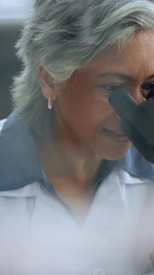 Woman Scientist Looks Through Microscope in the Lab
