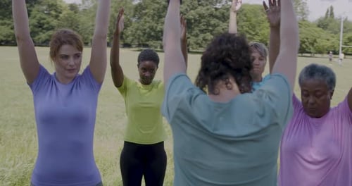 Women's Exercise Class Stretching Arms in Park