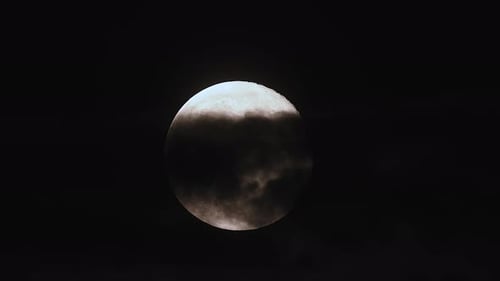 Bright Moon Partially Obscured by Clouds at Night