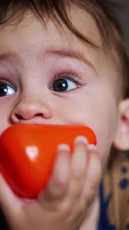 Un adorable petit garçon est allongé sur le ventre avec un jouet dans sa bouche.