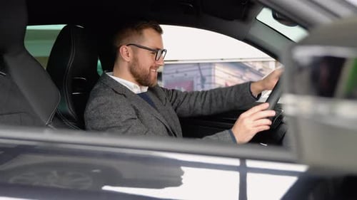 Happy Man Sits in New Electric Car in Shop Dealership and Celebrate Purchase of New Vehicle