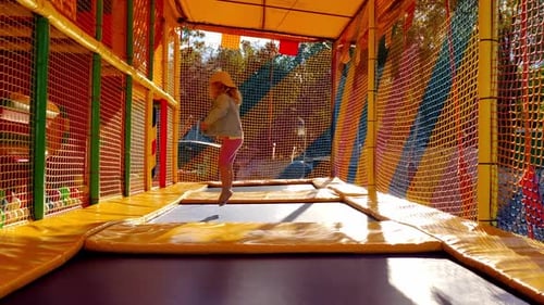 Cheerful Child Jumps on Trampoline in Children Room on Street