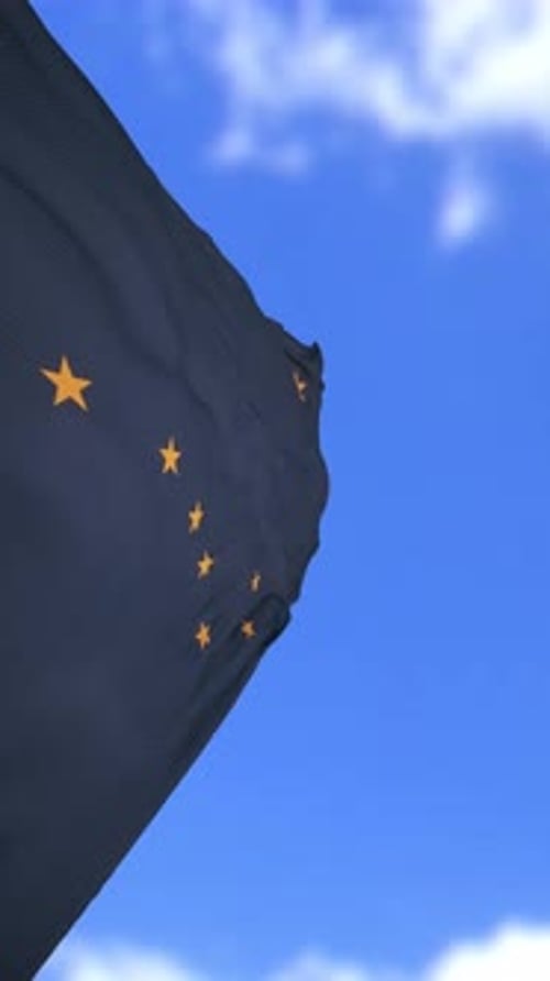 Drapeau de l'État de l'Alaska agitant contre un ciel bleu vif avec de légers nuages