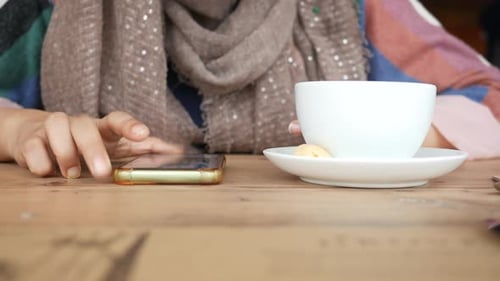 Women Hand Using Smart Phone and Drinking Coffee in a Cafe