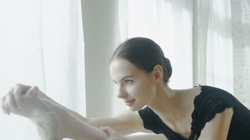 Close-up of a Young and Beautiful Ballerina Doing Leg Stretching at the Barre. Shot on a Sunny Morn