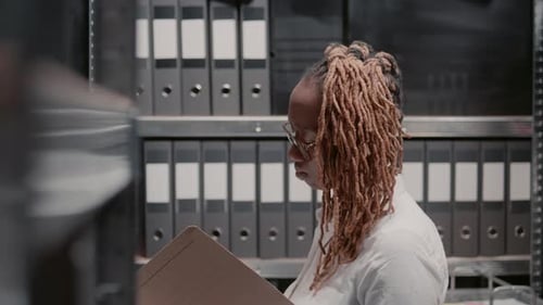 Woman Looks Through Files in Office Storage Room