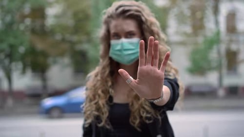 Woman in Mask Holds Up Hand to Stop