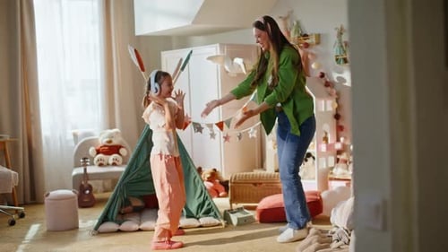 Mother and daughter dance together in colorful bedroom