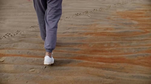 Closeup of a Person Walking on Textured Sandy Beach with Distinct Ripple Patterns