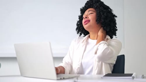 Woman Massaging Neck While Using Laptop At Desk